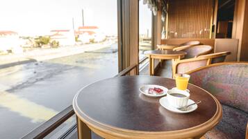 A round wooden table with a plate, cup, and glass of orange juice.