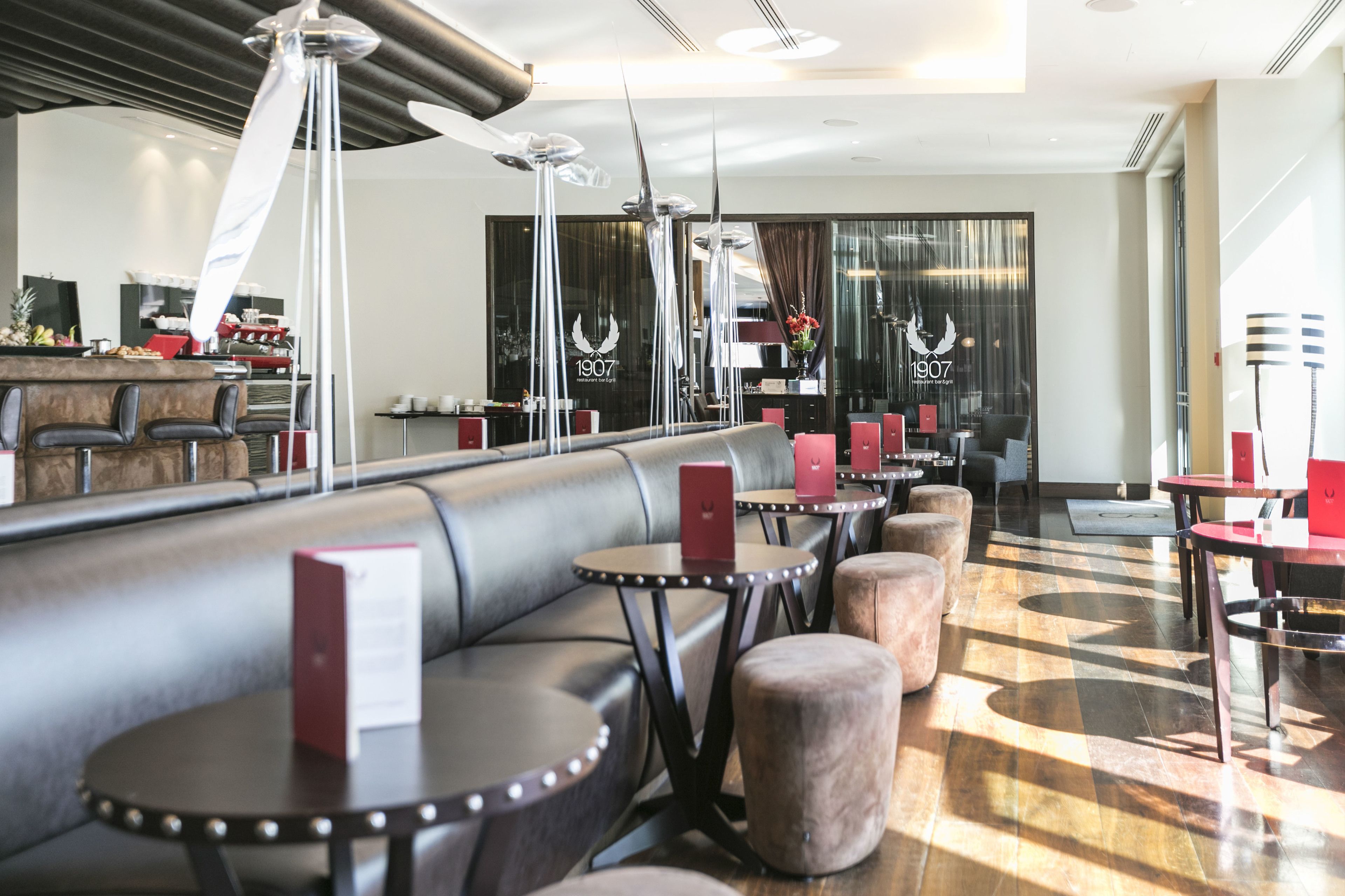 Ein modernes Restaurant mit Ledersitzgelegenheiten, runden Tischen und dekorativen Metallelementen.