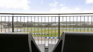 A view from a balcony with a metal railing, overlooking a race track with blue and white barriers.