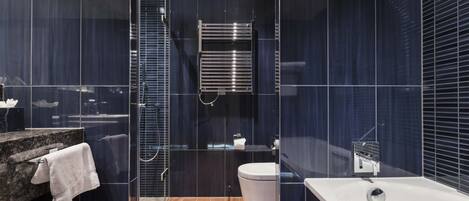 A modern bathroom with a glass-enclosed shower, a white toilet, and a marble countertop with a towel.