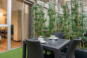 An indoor dining area with a table set for two, surrounded by bamboo plants. - Sea Land Suites - by Echo Hotels (Tel Aviv)