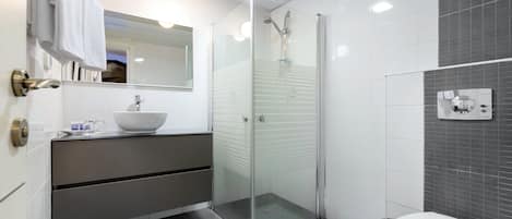 A modern bathroom with a glass-enclosed shower, a white sink, and a toilet.