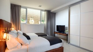 A modern bedroom with a large bed, a TV, and a sliding door. - Sea Land Suites - by Echo Hotels (Tel Aviv)