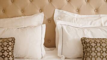 A bed with a tufted headboard, white bedding, and patterned throw pillows.