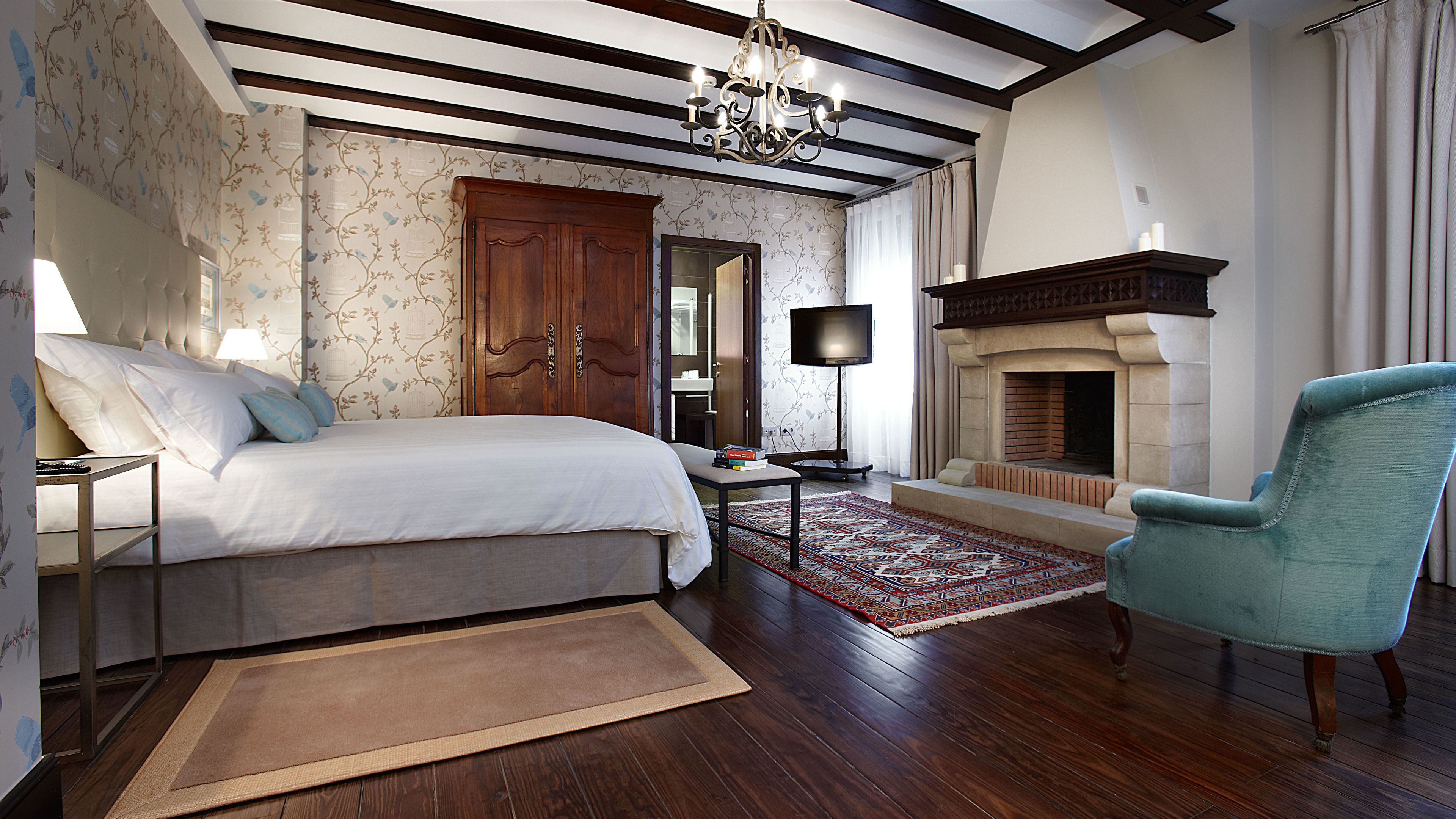 A bedroom with a bed, bedside table, lamp, and a fireplace.