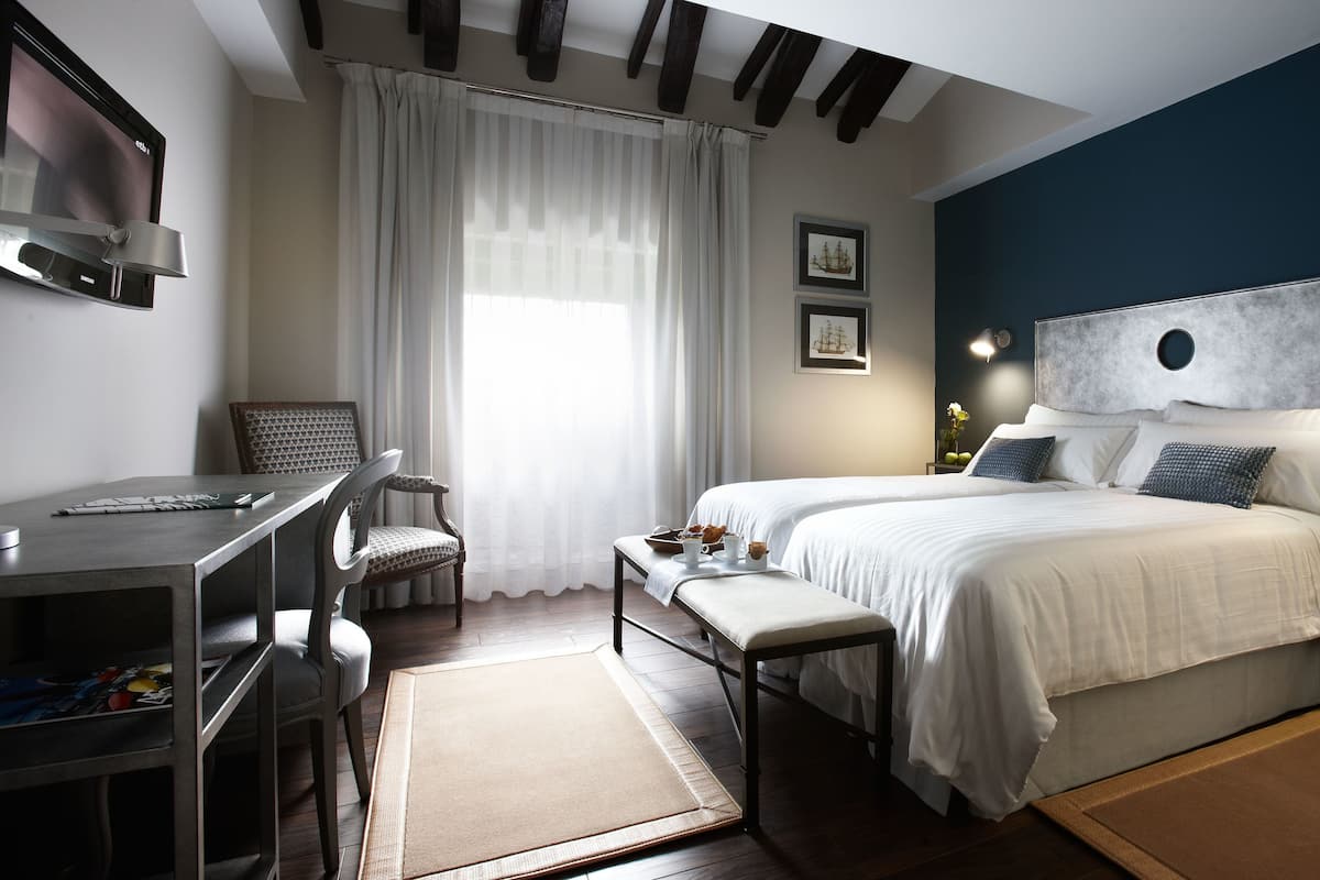 A modern bedroom with a large bed, bedside tables, a desk, and a chair.