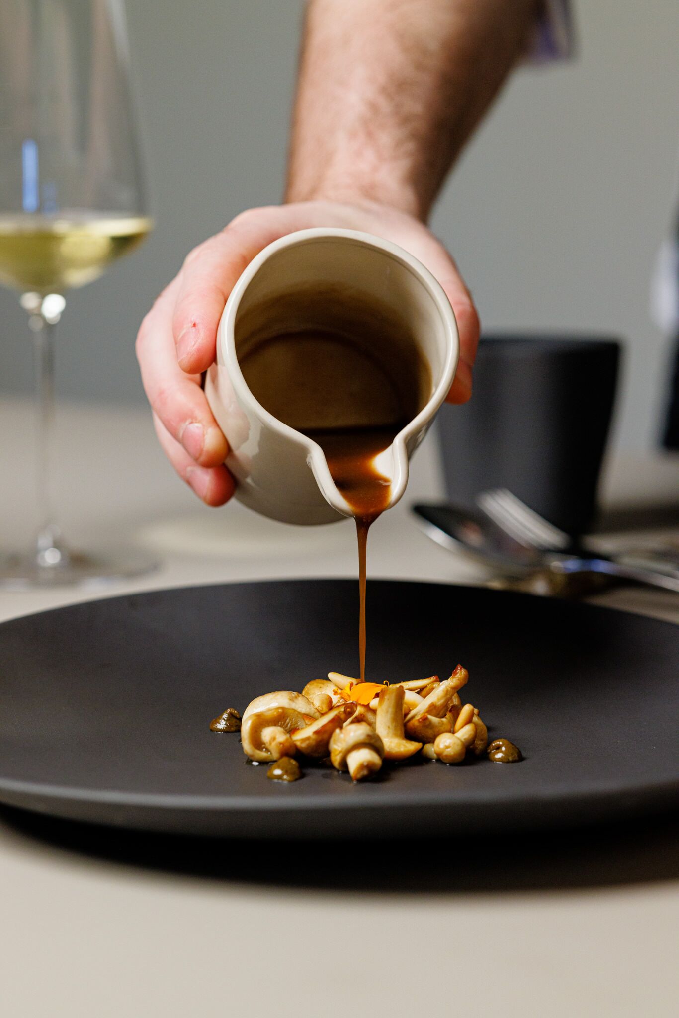A hand pouring sauce over a dish of food.