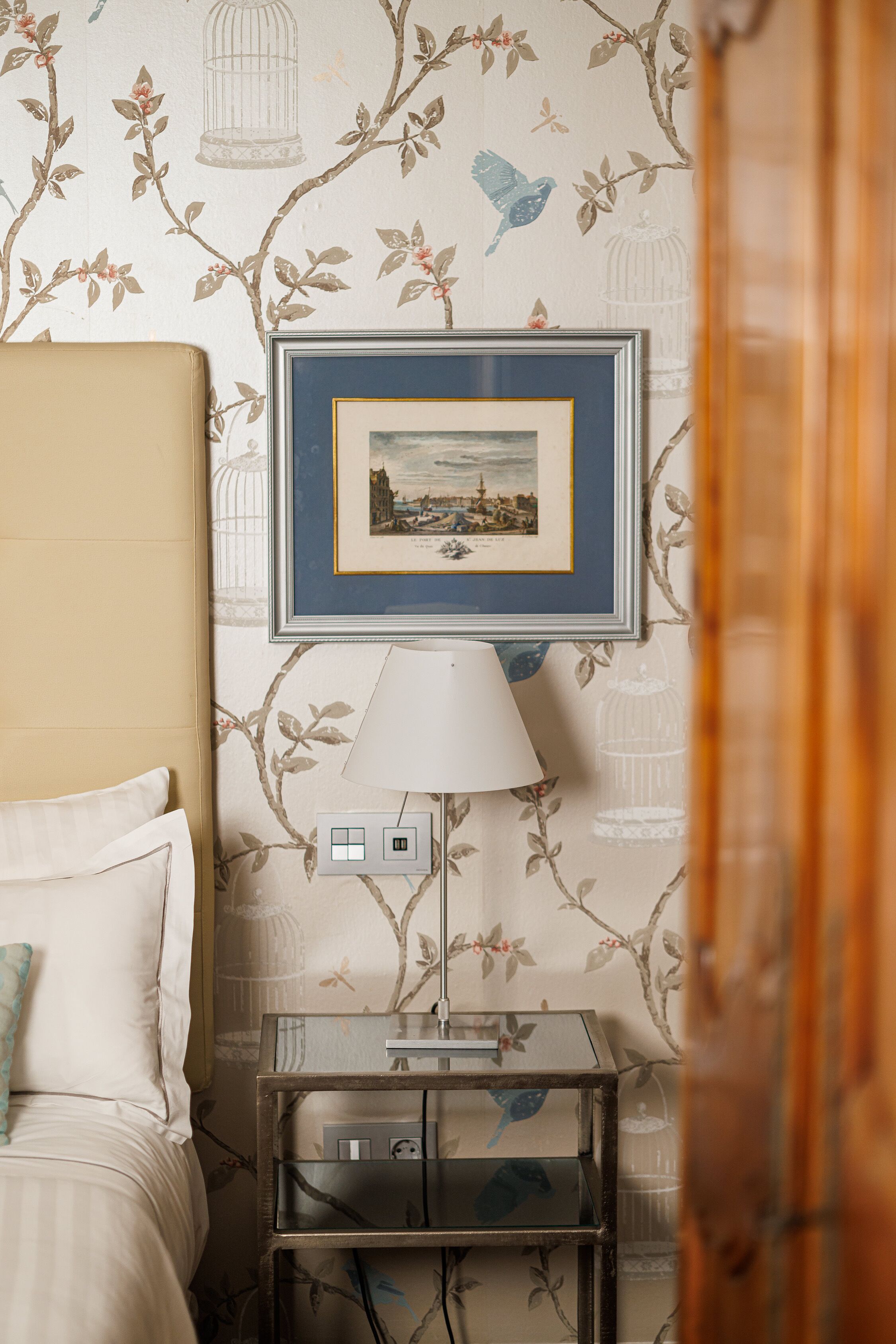 Une chambre d’hôtel bien rangée, avec un lit, une table de chevet dotée d’une lampe et un tableau encadré au mur.