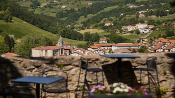 Un muro de piedra con asientos al aire libre, con vistas a un pueblo de edificios con tejados rojos y una iglesia.