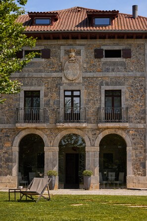 A stone building with a tiled roof, multiple windows, and a balcony. - Hotel Iriarte Jauregia (Bidania-Goiatz)