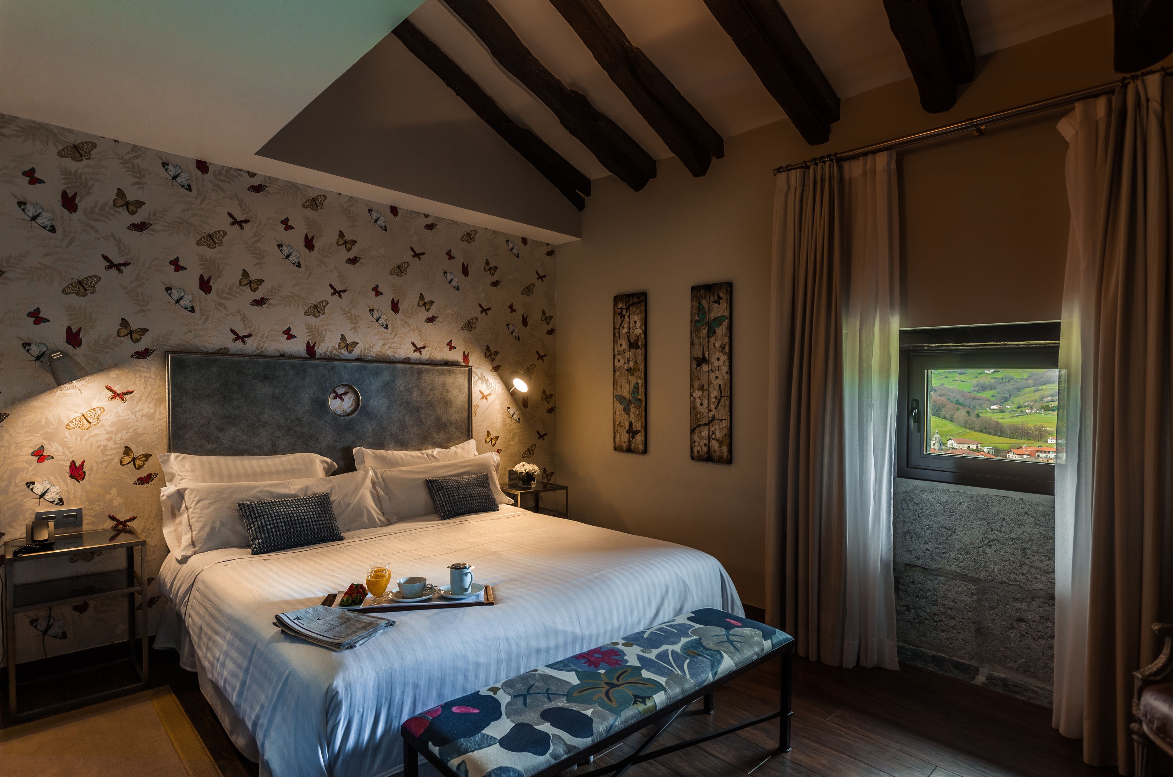 A bedroom with a bed, bedside tables, a window with curtains, and butterfly-themed wall decor.