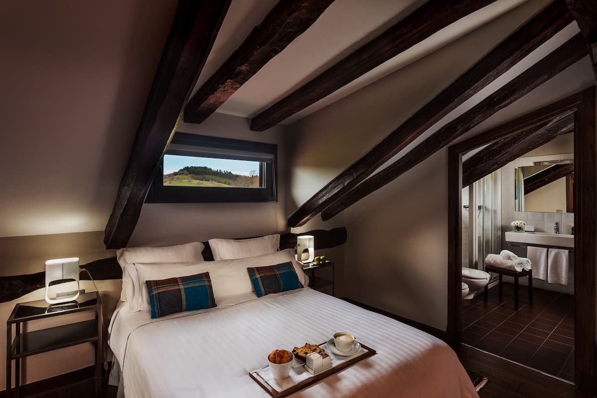 A bedroom with a bed, bedside table, and a tray with a muffin, coffee cup, and a box.