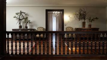 A room with a wooden railing, a chandelier, and two potted plants.