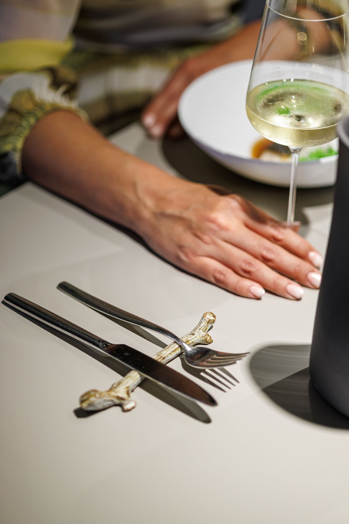 A dining table with a wine glass, a fork, and a knife.