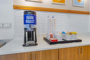 A coffee station with a coffee machine labeled 'DARK ROAST' and a stack of disposable cups. - Hampton Inn & Suites New Braunfels (New Braunfels)