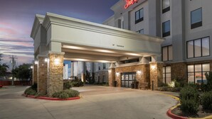 A Hampton Inn & Suites with a 14' clearance sign, stone pillars, and a well-lit entrance.