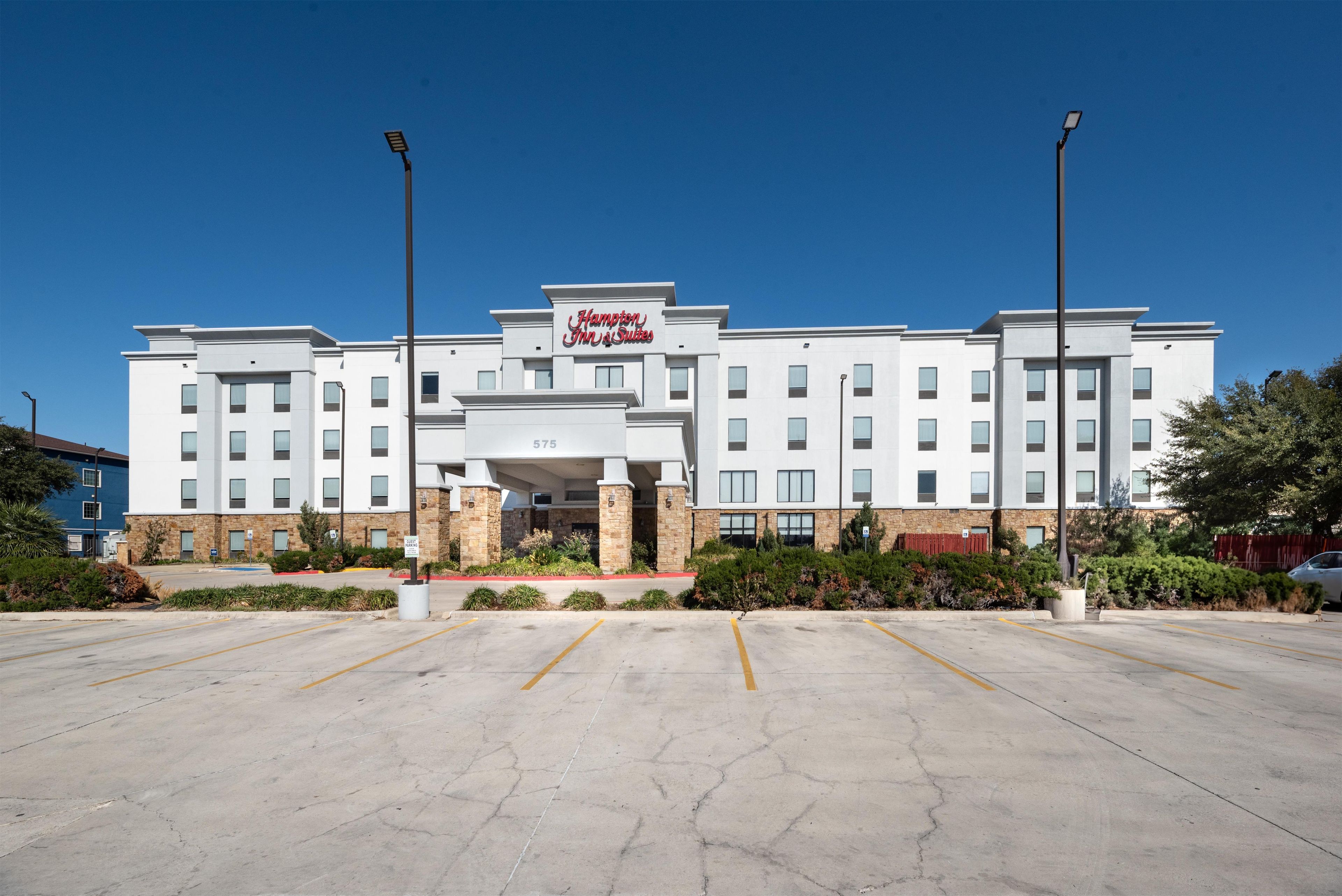 Um hotel Hampton Inn & Suites com um estacionamento em frente.