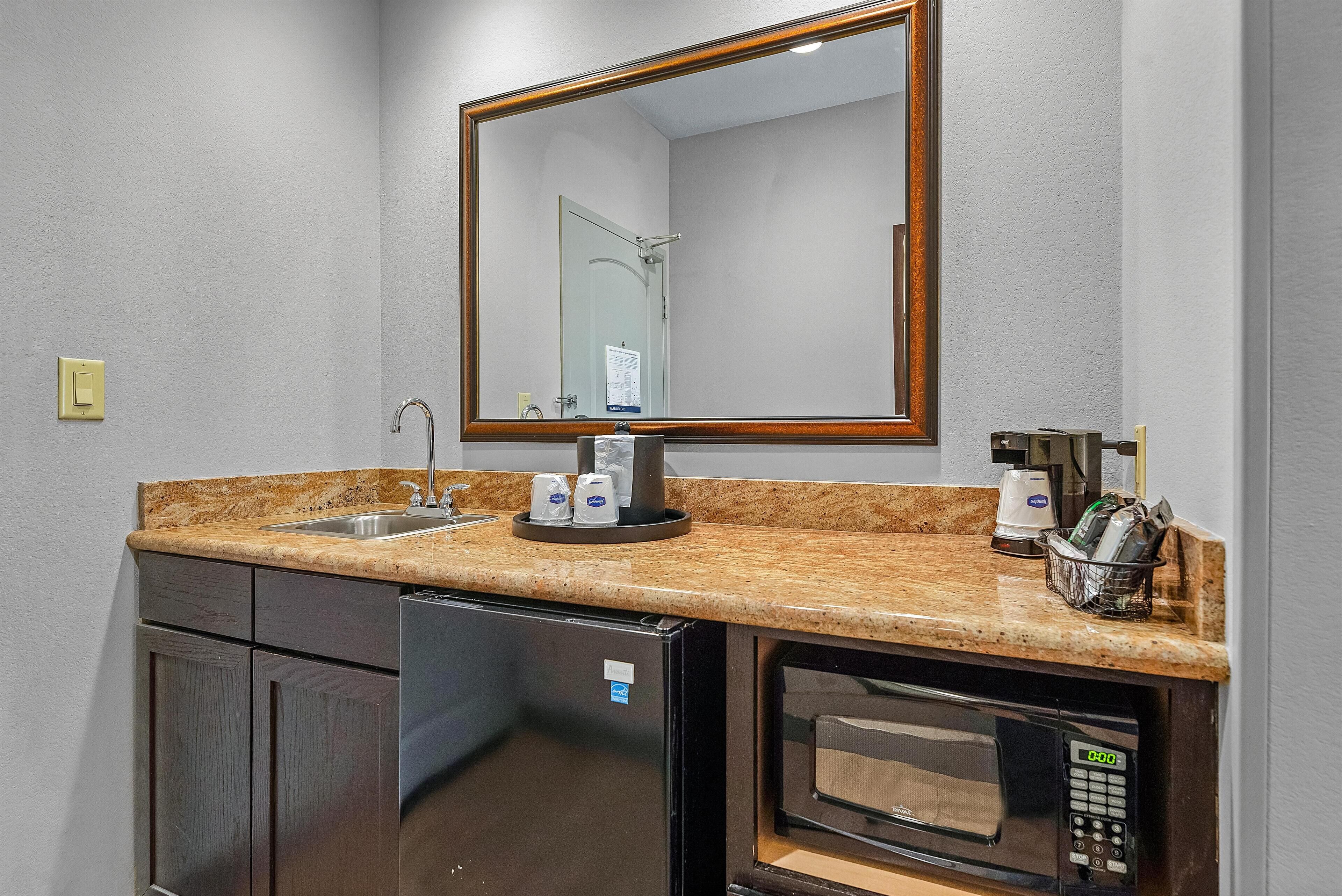 Una kitchenette compacta con pileta, cafetera y microondas.