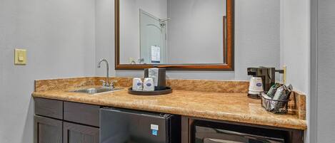 Una kitchenette compacta con pileta, cafetera y microondas.
