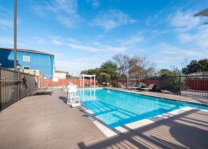 A swimming pool with a lifeguard chair, lounge chairs, and a covered seating area. - Hampton Inn & Suites New Braunfels (New Braunfels)