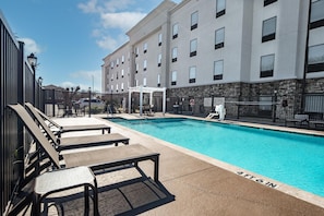 A swimming pool with lounge chairs and a building in the background.
