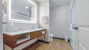Une salle de bain moderne avec un meuble-lavabo en bois, un grand miroir et un espace douche.