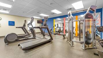 A gym with treadmills, a weight machine, and a mirrored wall.