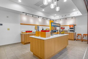 A modern kitchen area with a central island, wooden cabinets, and a juice dispenser.
