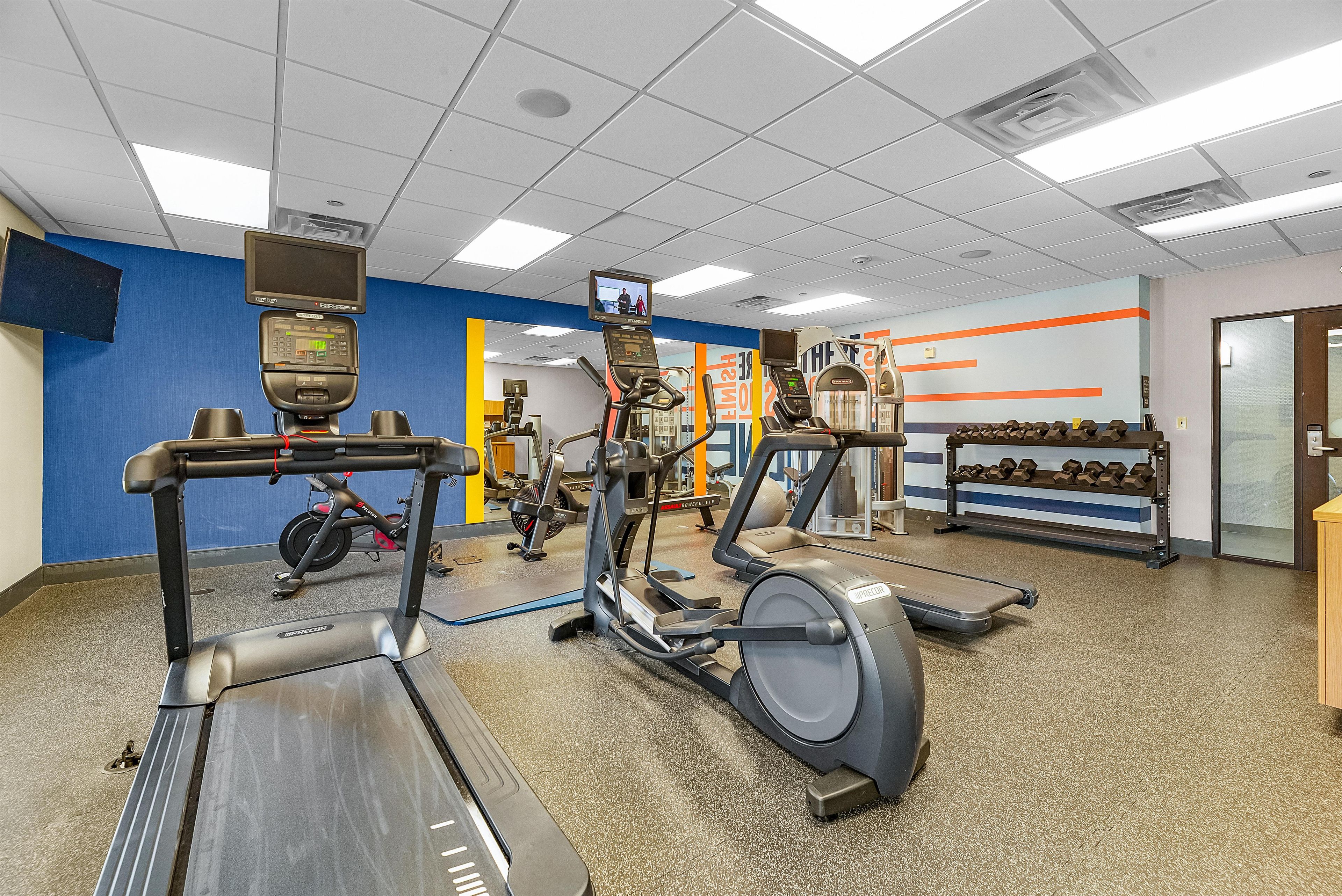 A gym with treadmills, elliptical machines, and weightlifting equipment.