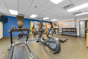 Una palestra con tapis roulant, macchinari ellittici e attrezzature per sollevamento pesi.