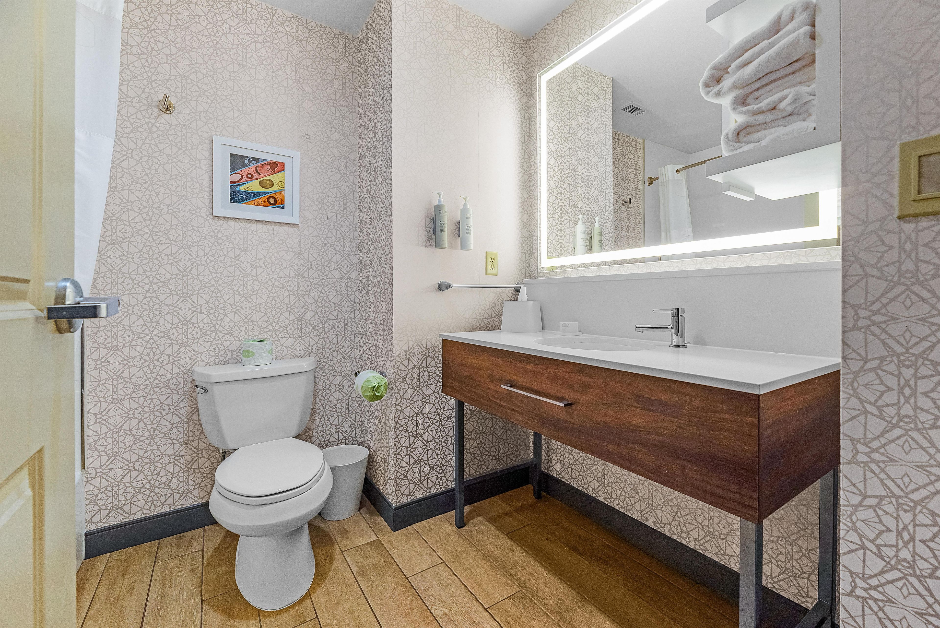 A modern bathroom with a toilet, sink, and mirror.