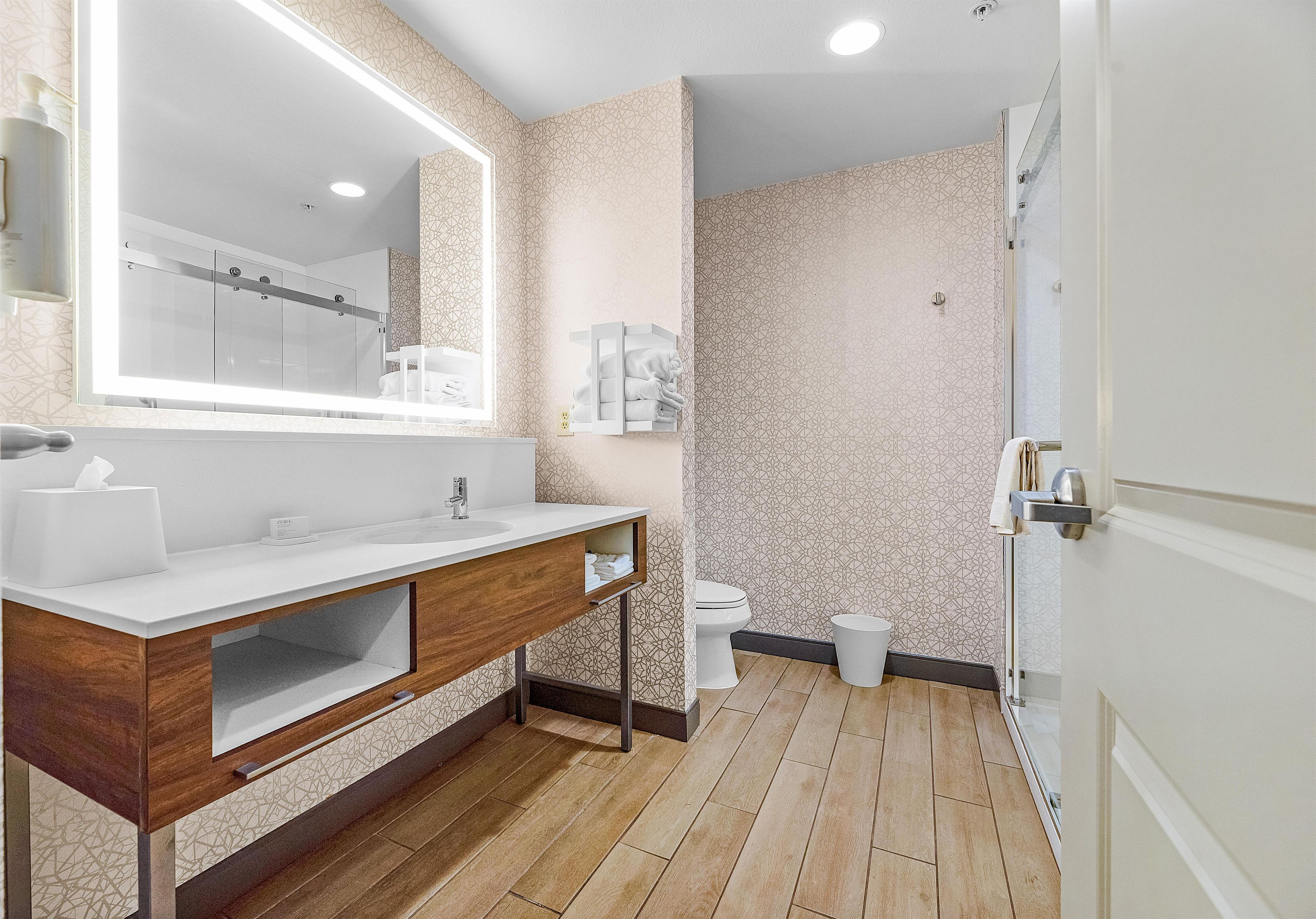 Une salle de bain moderne avec un grand miroir, deux lavabos, un meuble-vasque avec rangements, des toilettes et un espace douche.