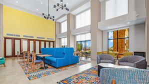 A spacious lobby with a blue sofa, wooden chairs, and a patterned rug.