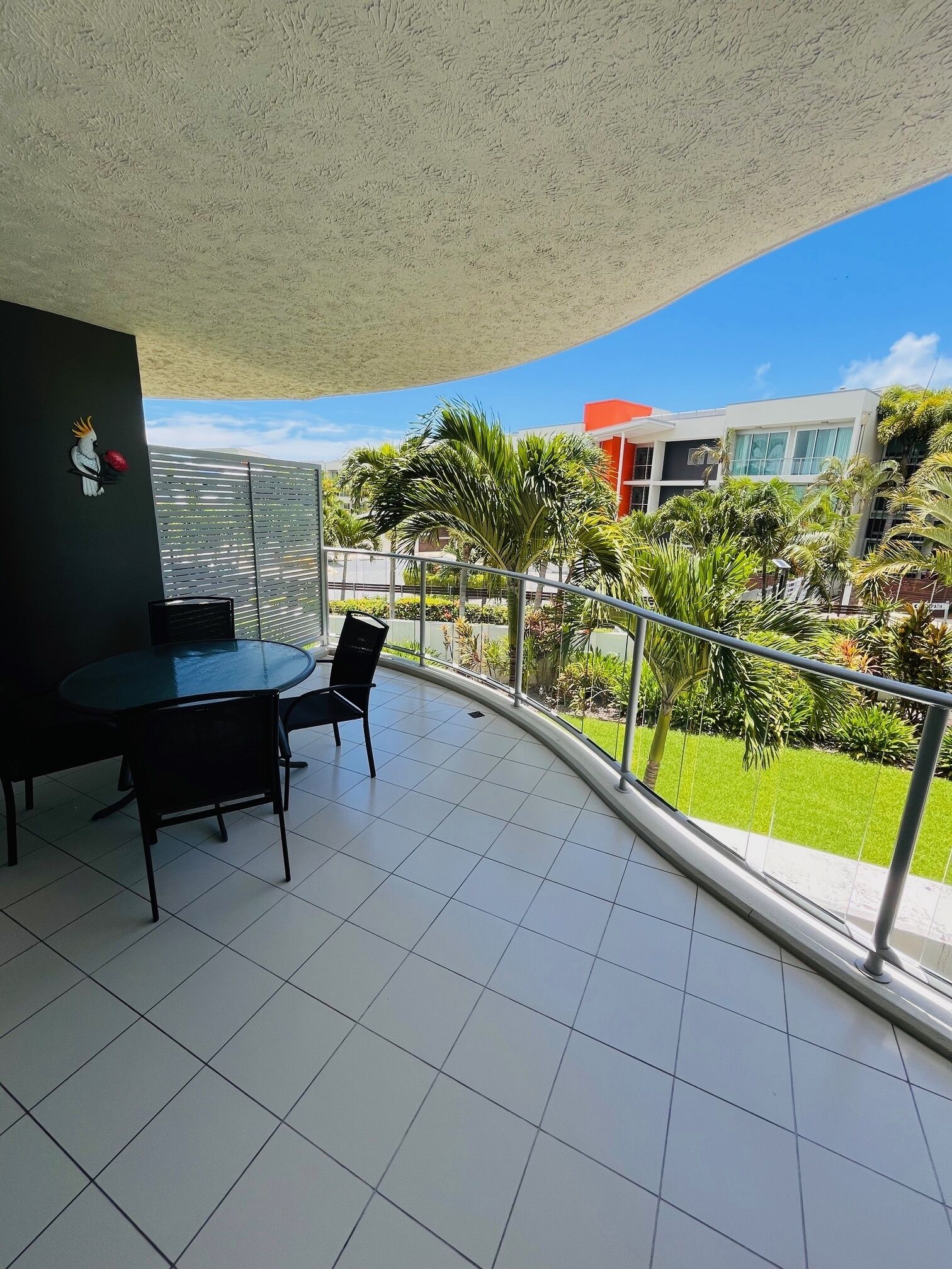 Un balcon doté d’un sol carrelé, d’une table avec des chaises et d’un élément décoratif mural.