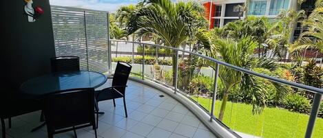 Un balcon doté d’un sol carrelé, d’une table avec des chaises et d’un élément décoratif mural.