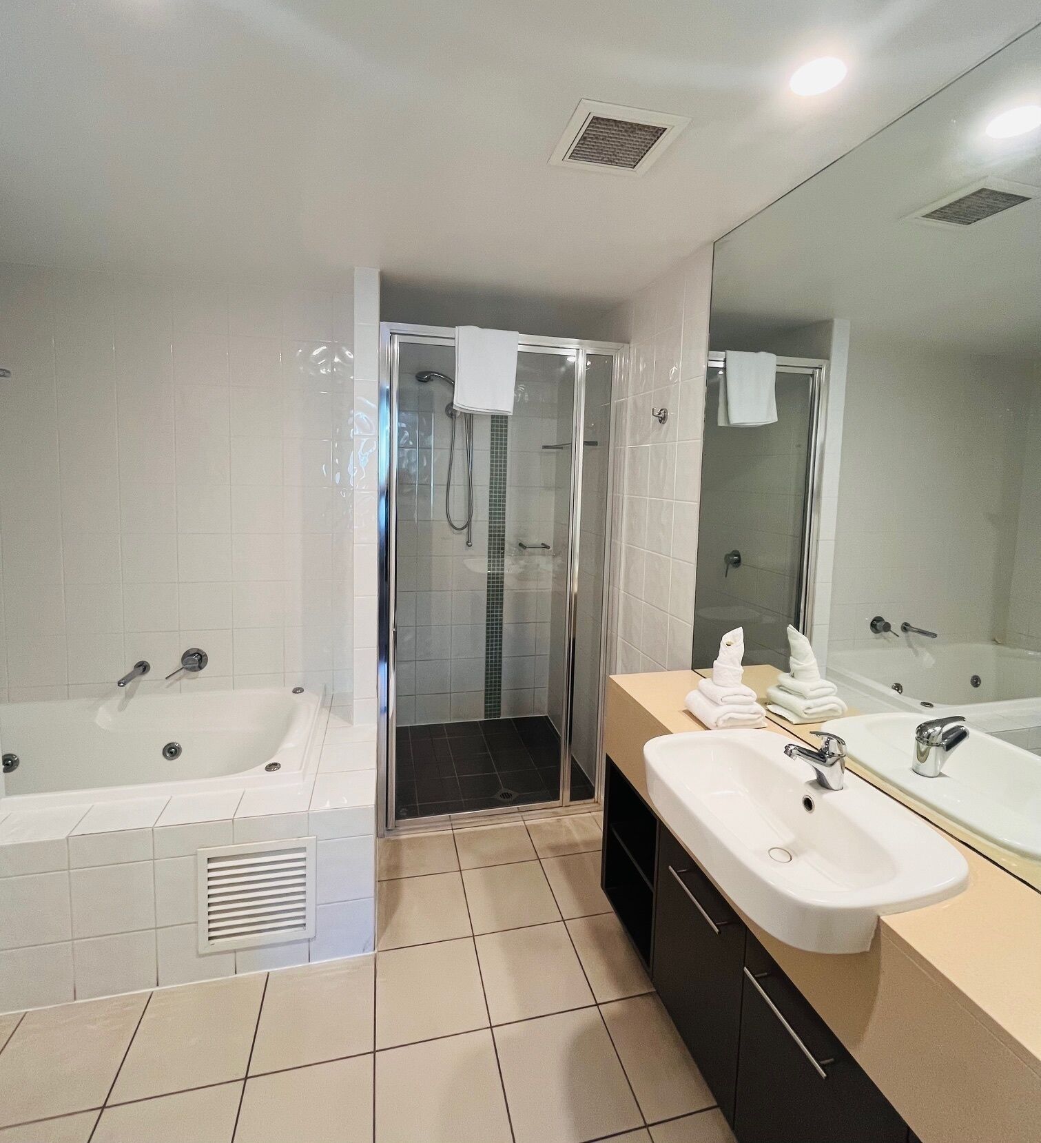 A modern bathroom with a bathtub, a shower enclosure, and a vanity with a sink and mirror.