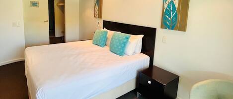 A hotel room with a bed, a nightstand, a chair, and artwork on the walls.