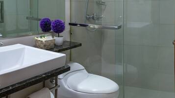 A modern bathroom with a white sink, toilet, and glass shower enclosure.