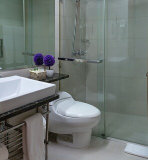 A modern bathroom with a white sink, toilet, and glass shower enclosure. - Hotel Aladino (Santo Domingo)