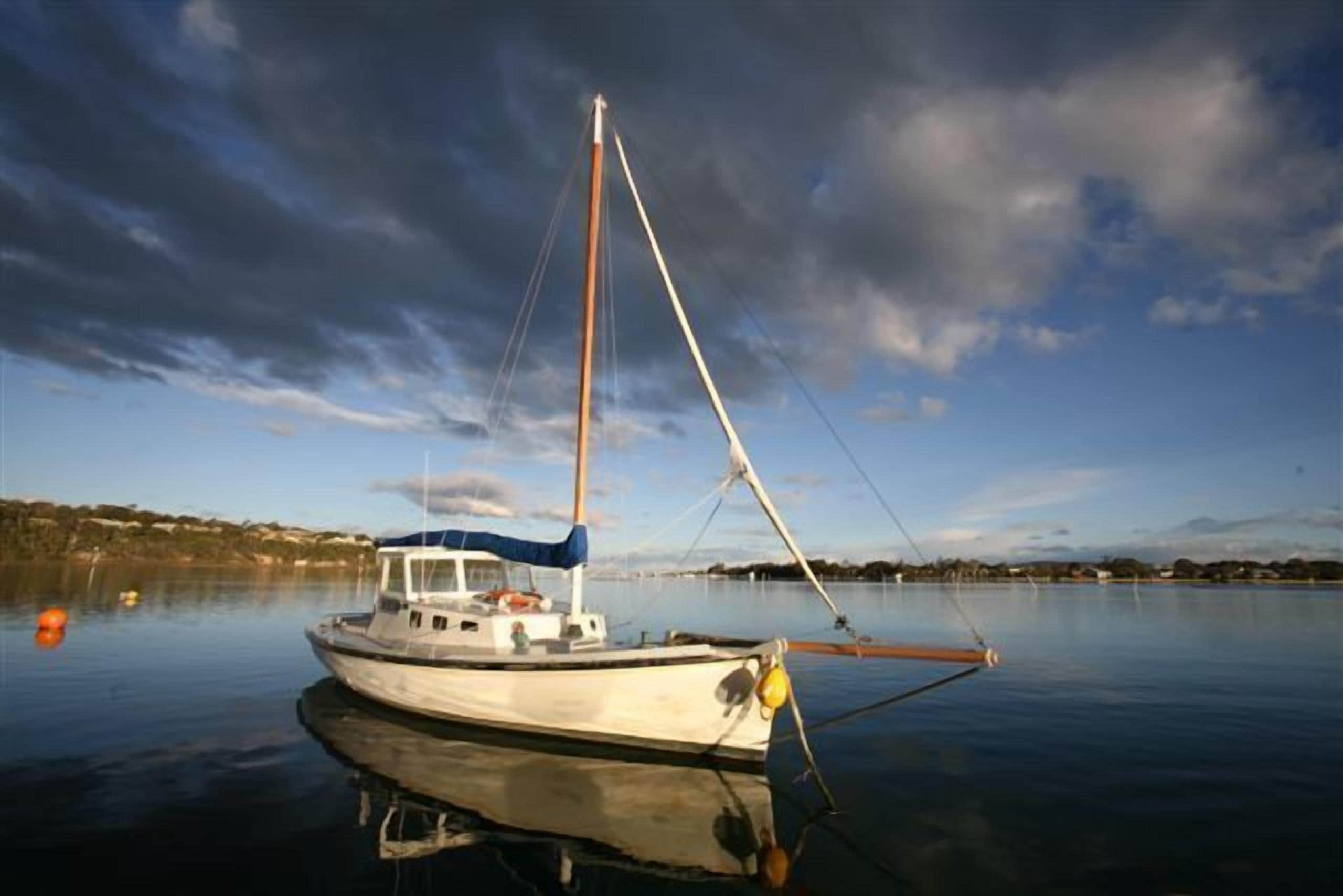 A small boat docked at a calm body of water with a clear sky and distant land in the background.