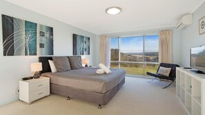 Quarto com uma cama grande, televisão e vista para o campo.