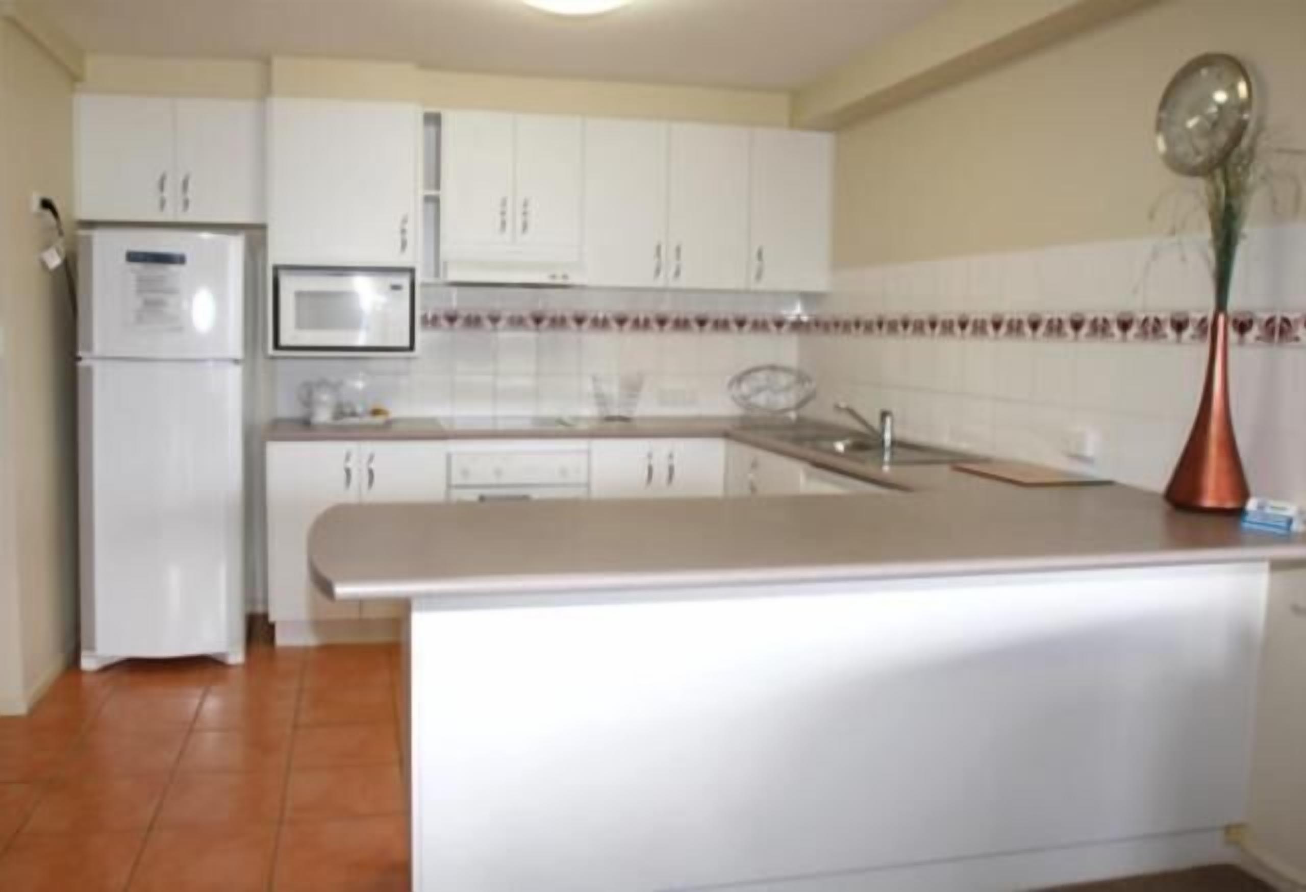 Cuina amb armaris blancs, microones i un rentaplat.