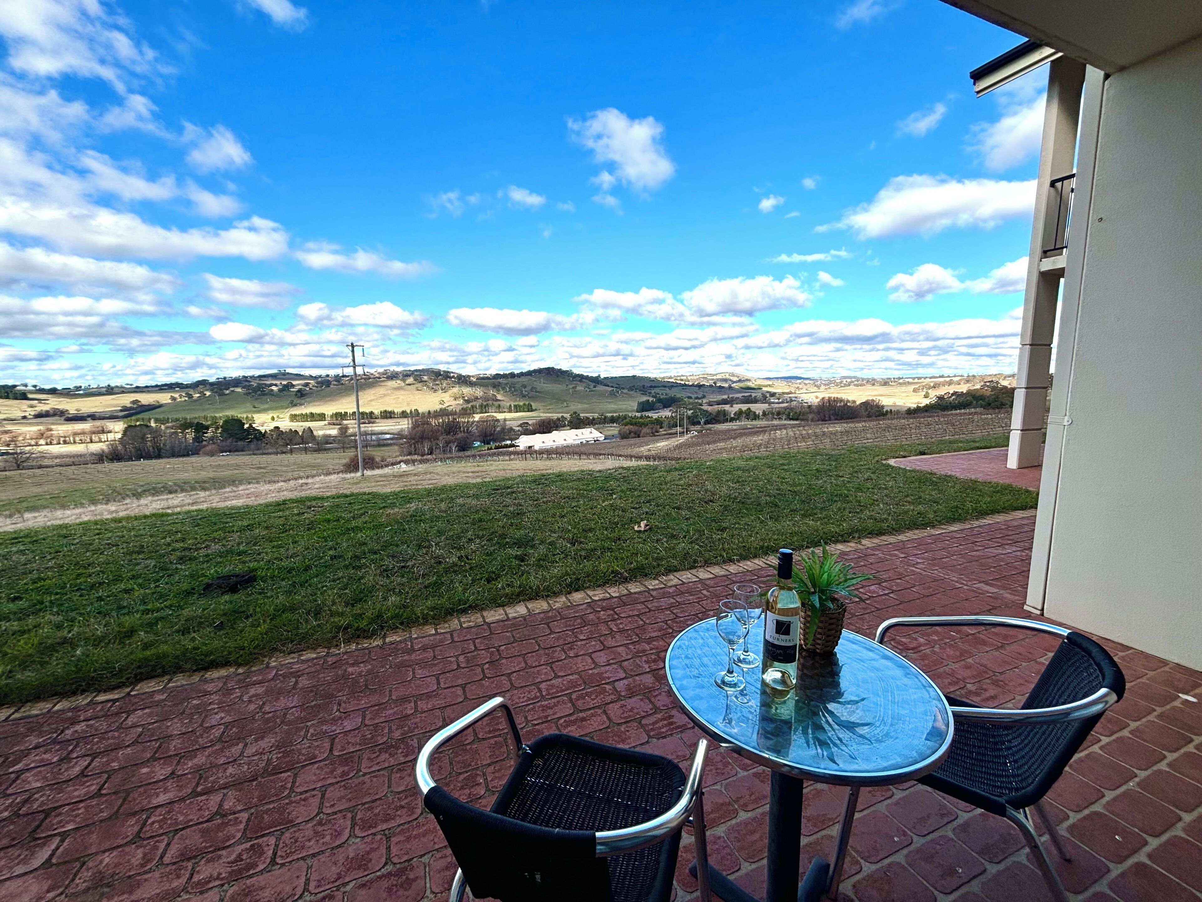 A patio with a table and chairs overlooking a rural landscape.