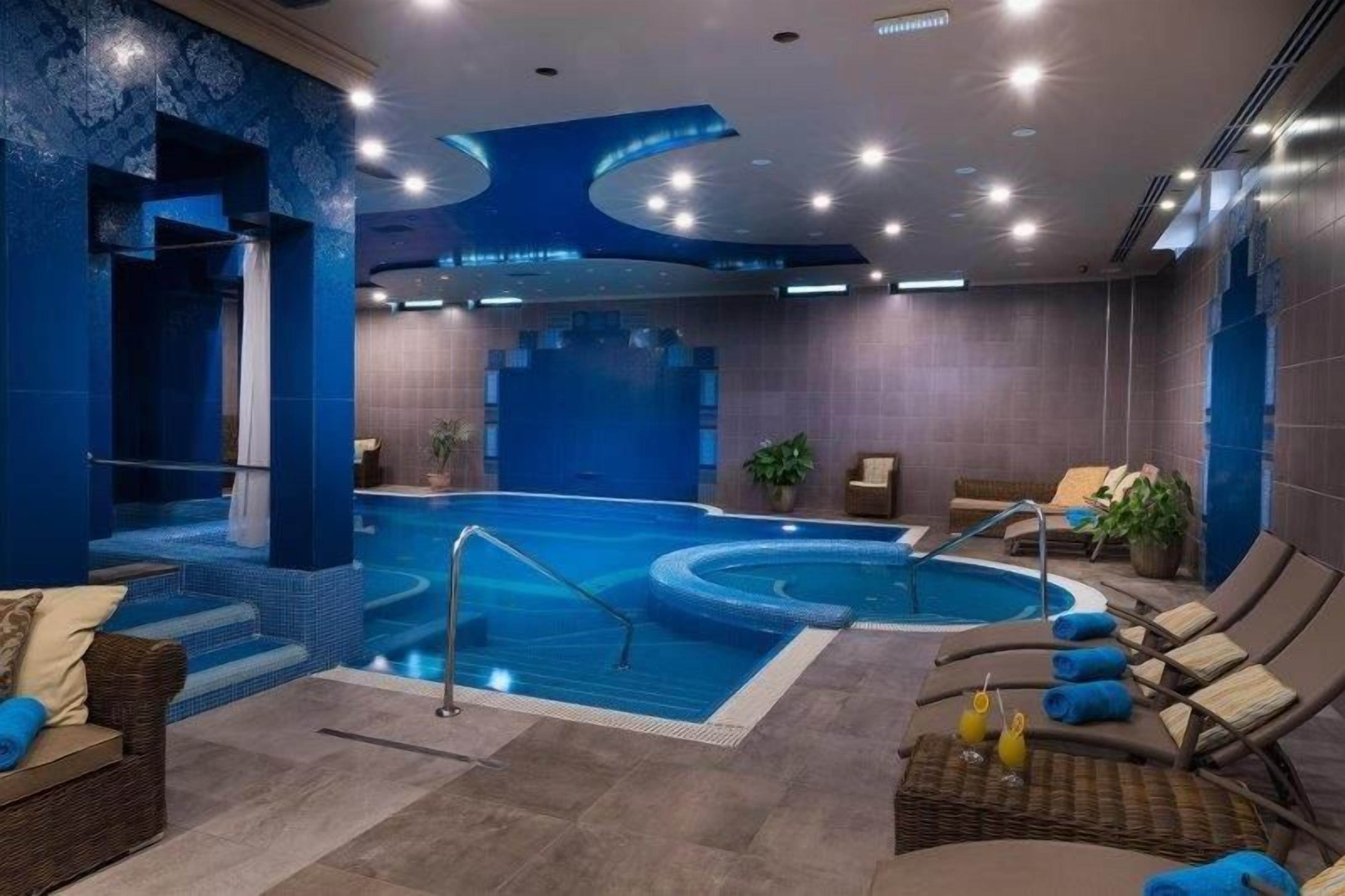 Un área de spa con hidromasaje, sillas de descanso y piscina.