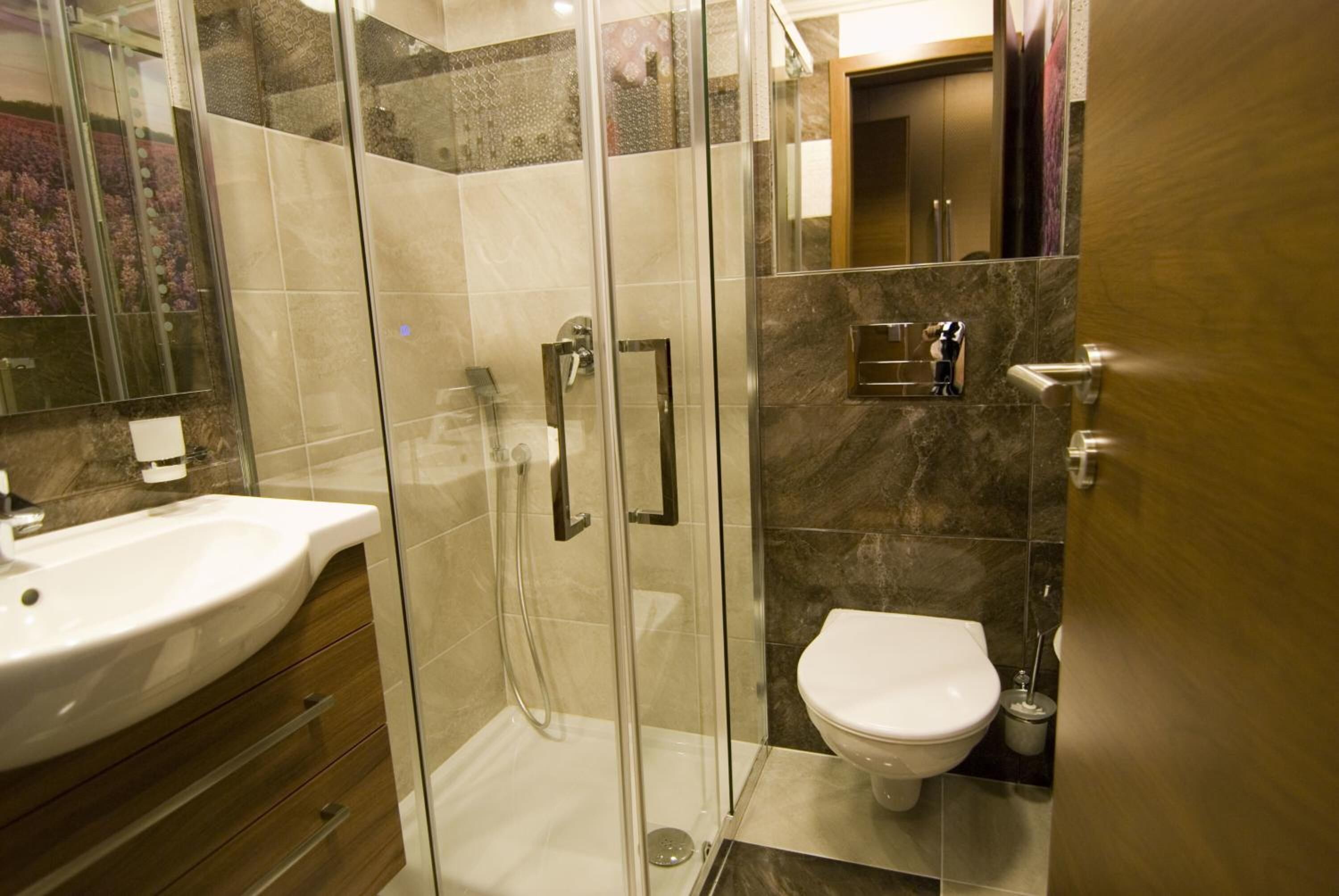 Un baño moderno con cabina de ducha de vidrio, un lavamanos blanco y un inodoro.