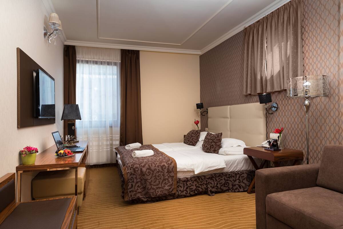 A hotel room with a bed, desk, chair, and a TV.
