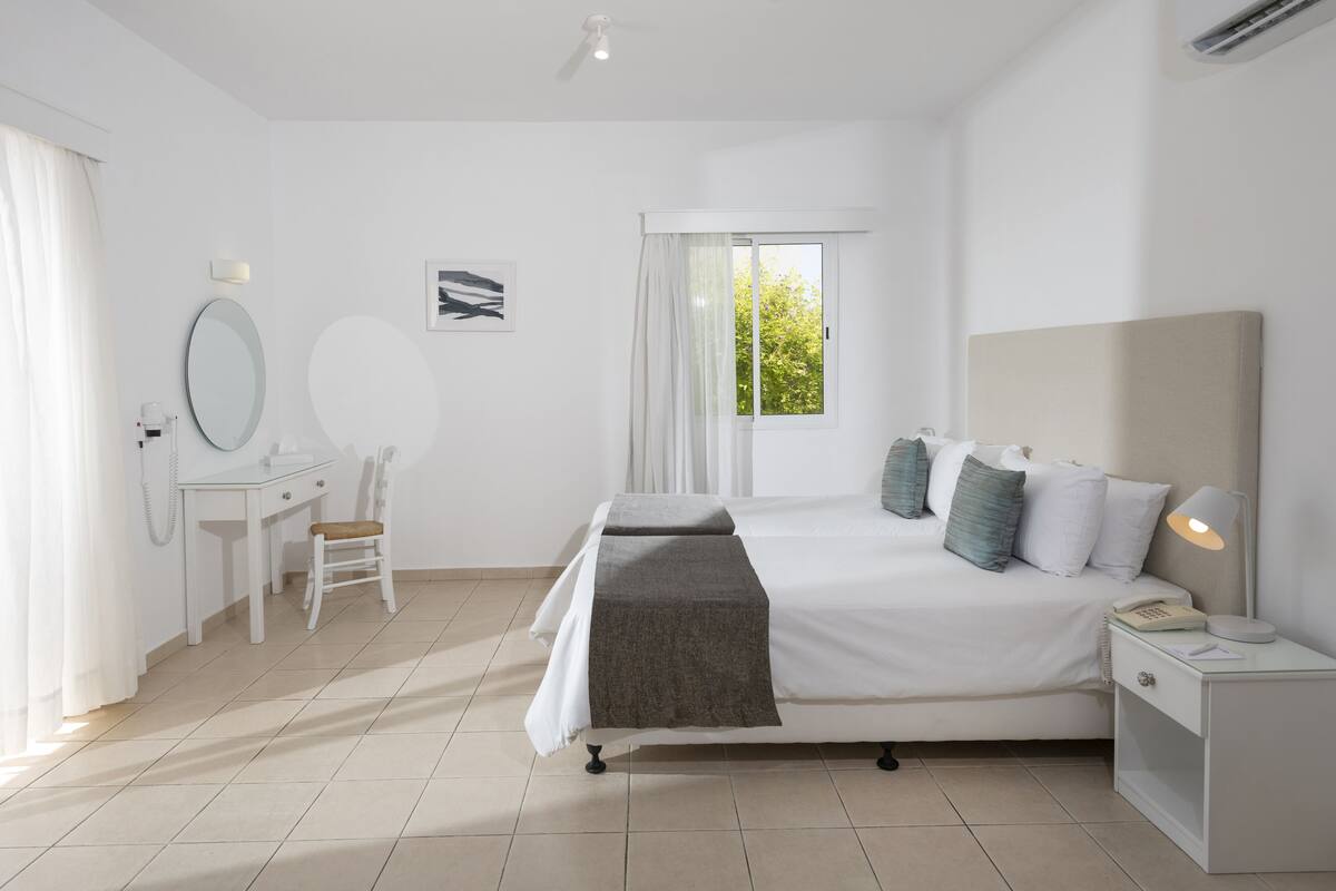 A modern bedroom with a bed, bedside table, and a desk with a chair.