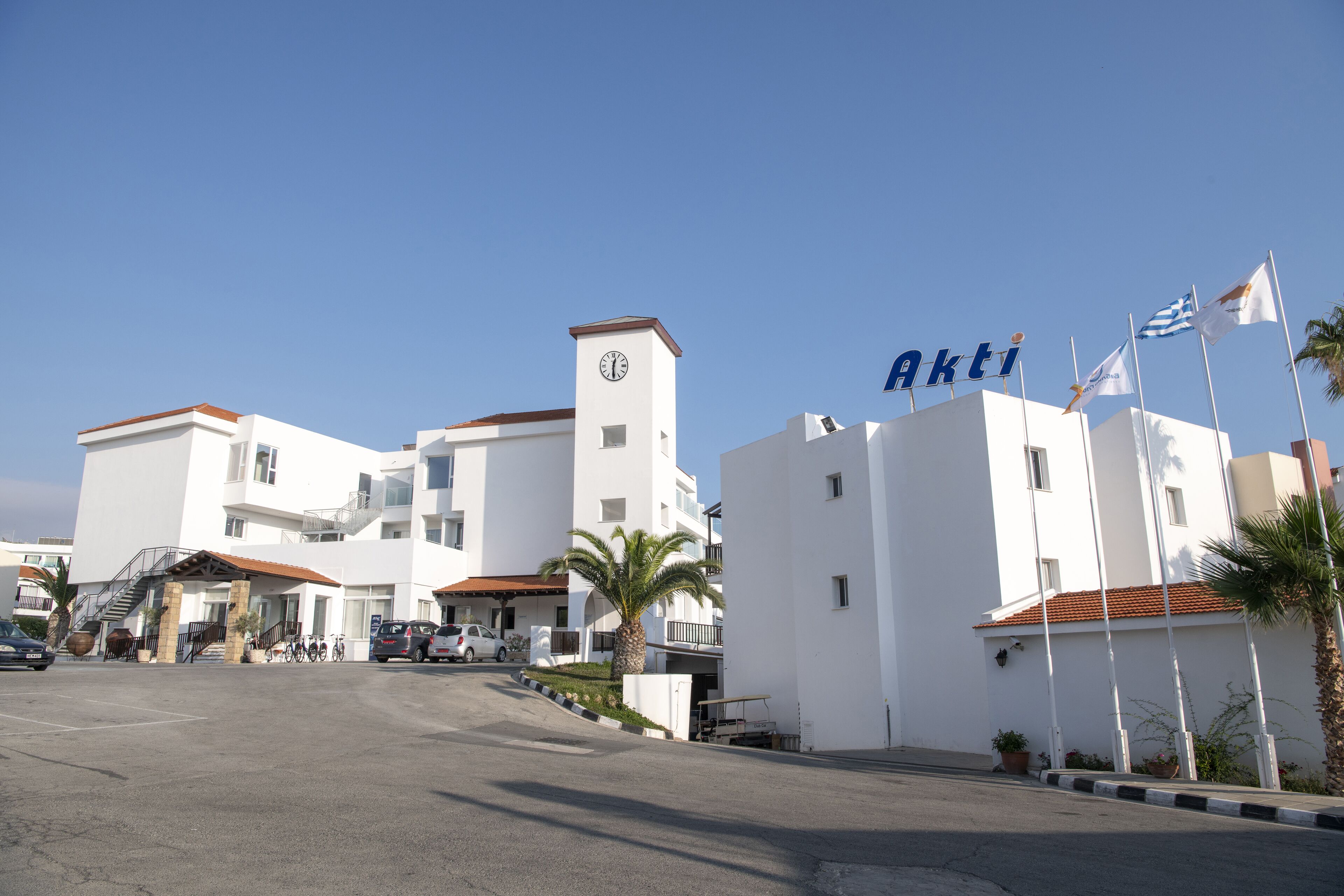 Un edificio moderno con una torre de reloj, un letrero que dice "Akti" y varias banderas.