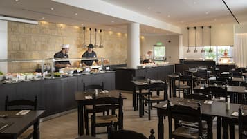 A buffet area with multiple food stations, a stone wall, and a seating area with tables and chairs.