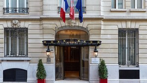 A grand building with ornate architectural details, a prominent entrance with a canopy, and flags of France and the European Union. - Majestic Hotel - SPA Champs Elysées (Paris)